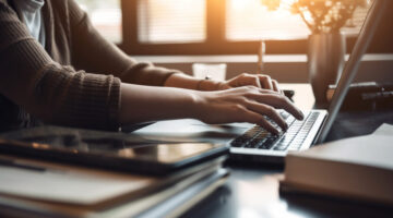 A businesswoman sitting at desk, using laptop generated by AI