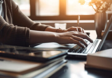 A businesswoman sitting at desk, using laptop generated by AI